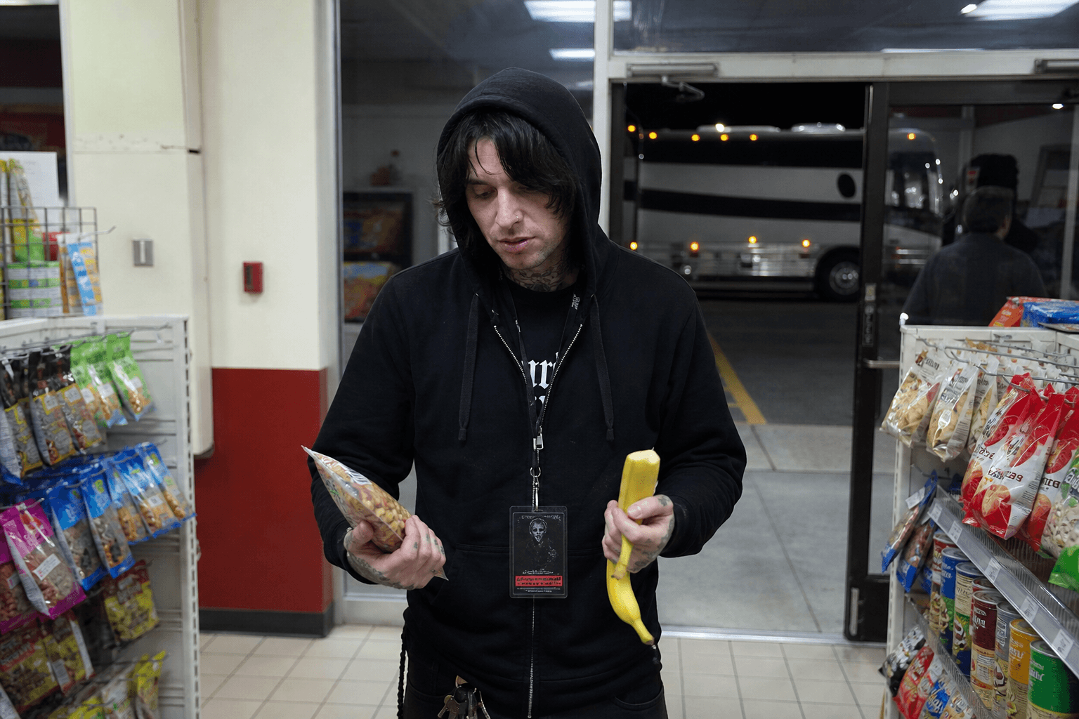 Roadie in a gas station snack aisle with the tour bus outside