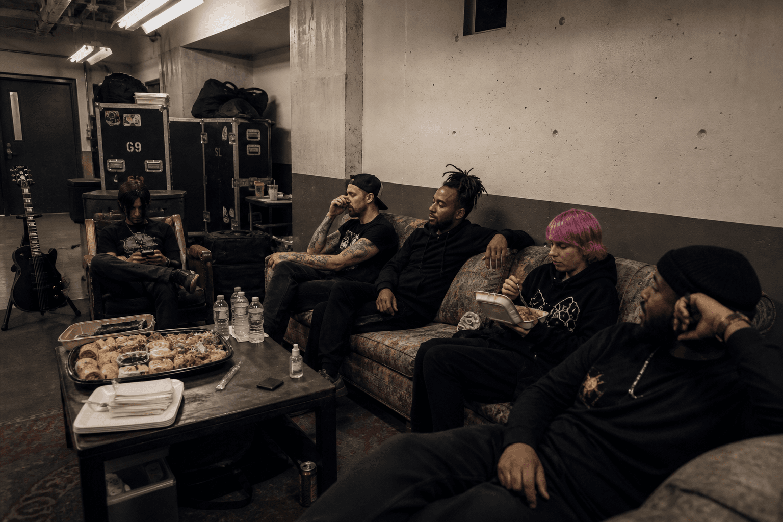 Crew sitting in a green room with cases and a catering tray
