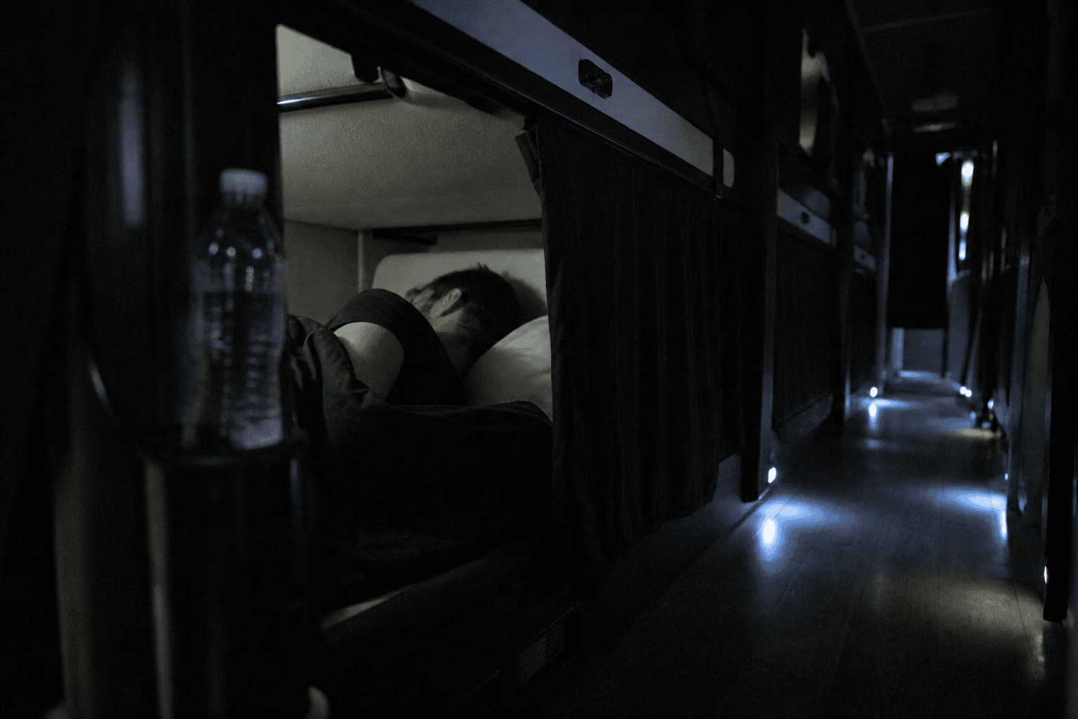 Tour bus bunks at night with a curtain half open