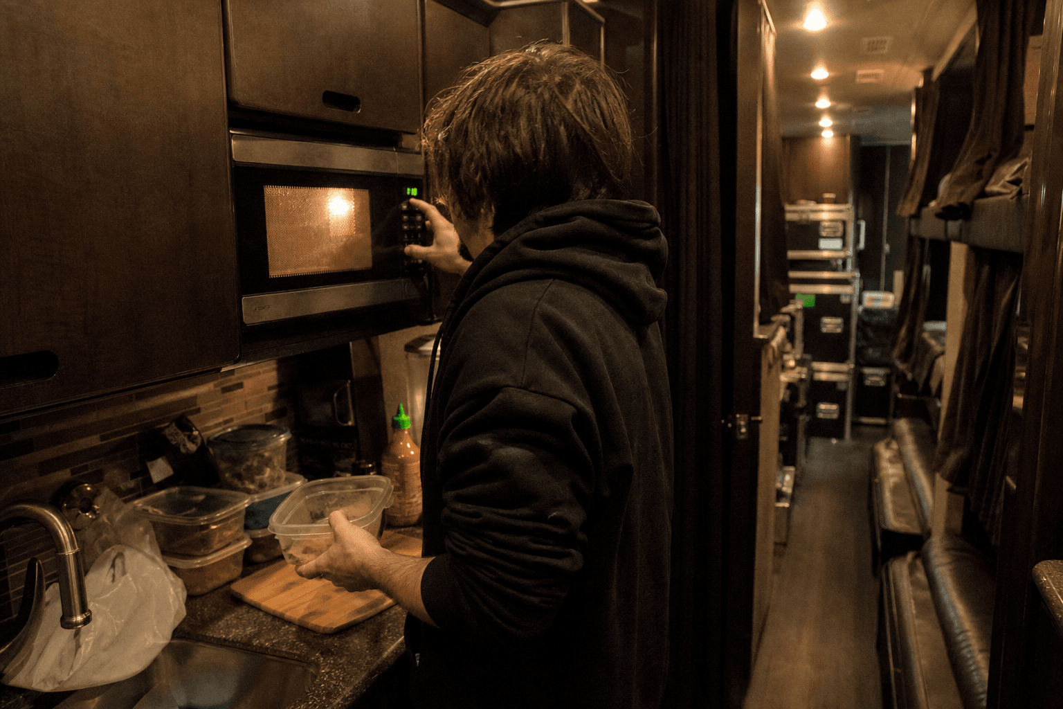 Roadie reheating food in a cramped tour bus kitchenette