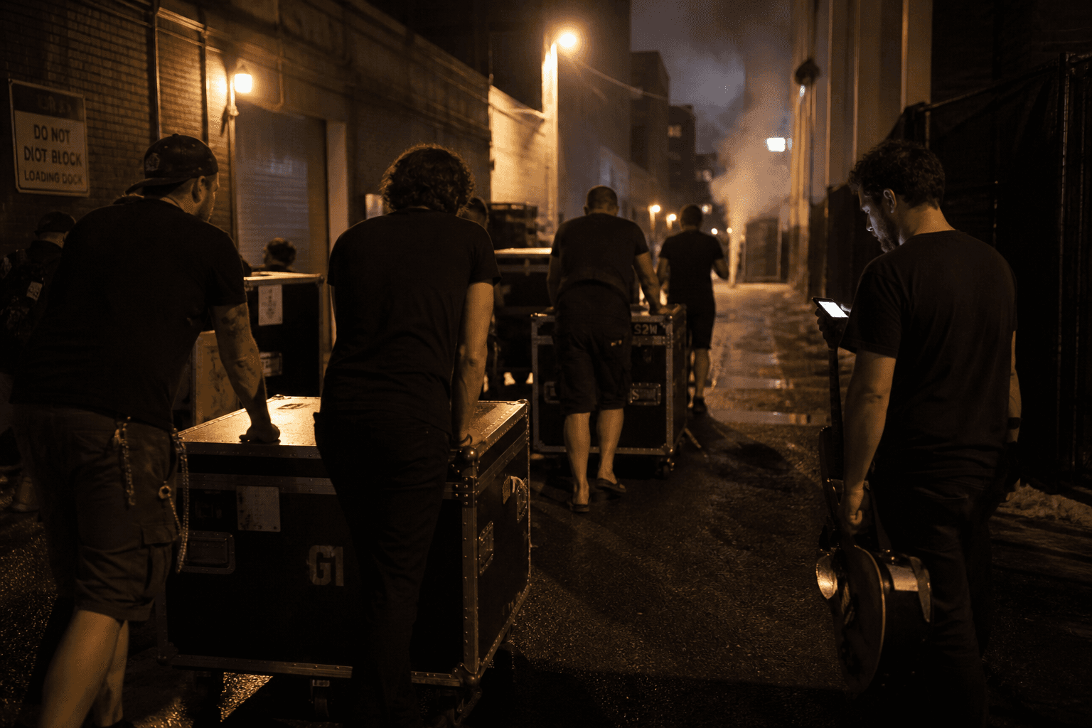 Crew pushing road cases down an alley after load-out